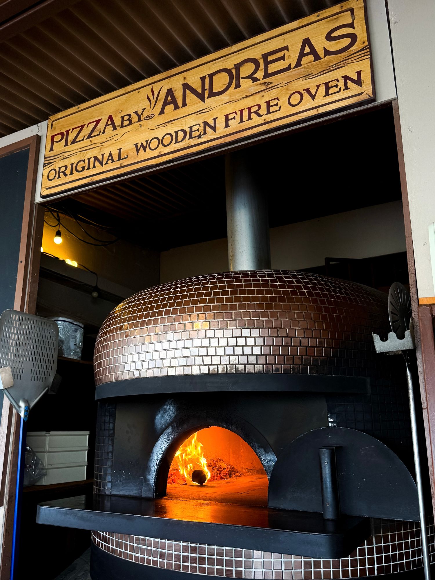 Pizza by Andreas original wooden fire oven sign above the lit oven