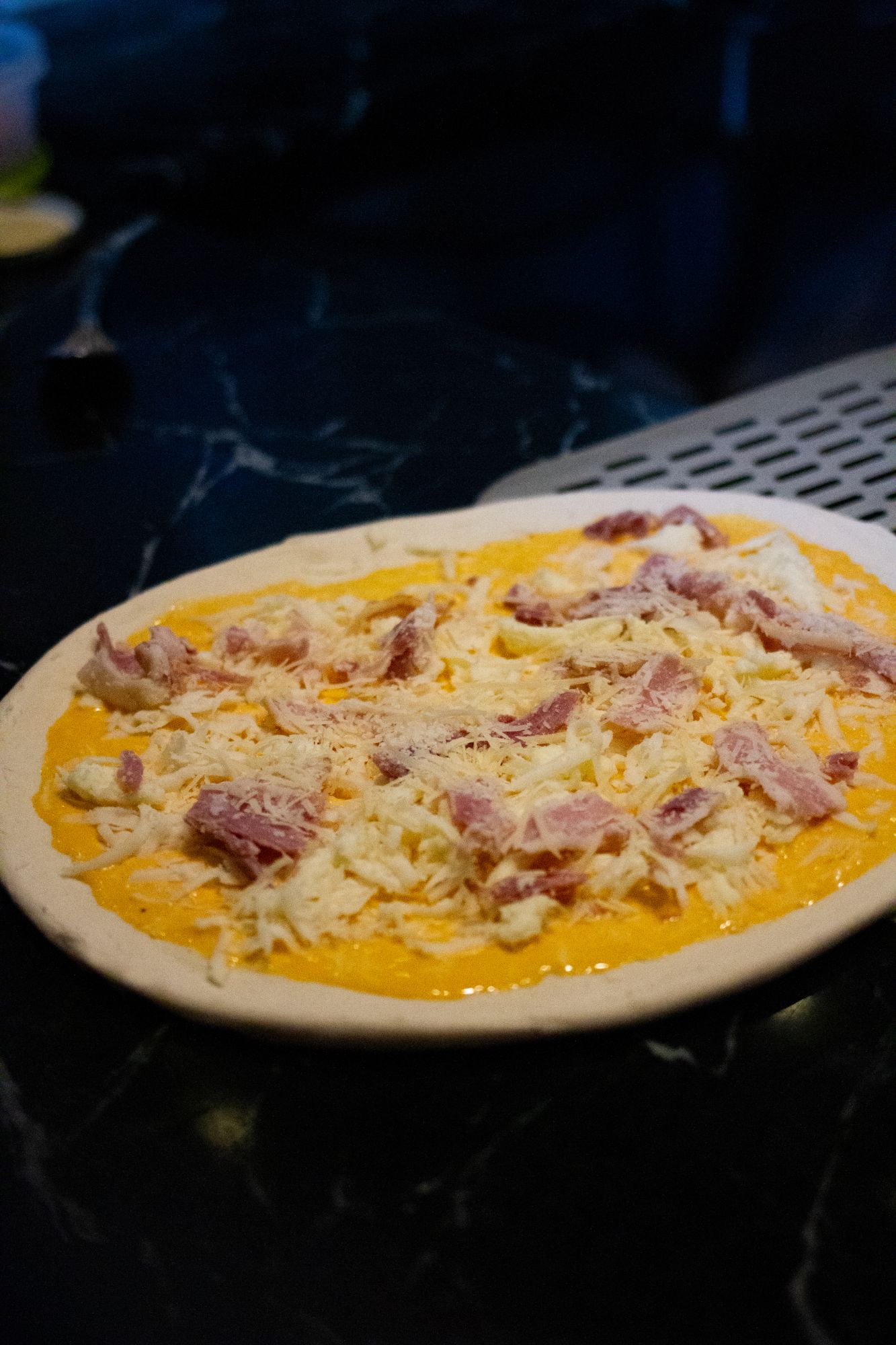 Bianca pizza topped with ham and cheese before baking