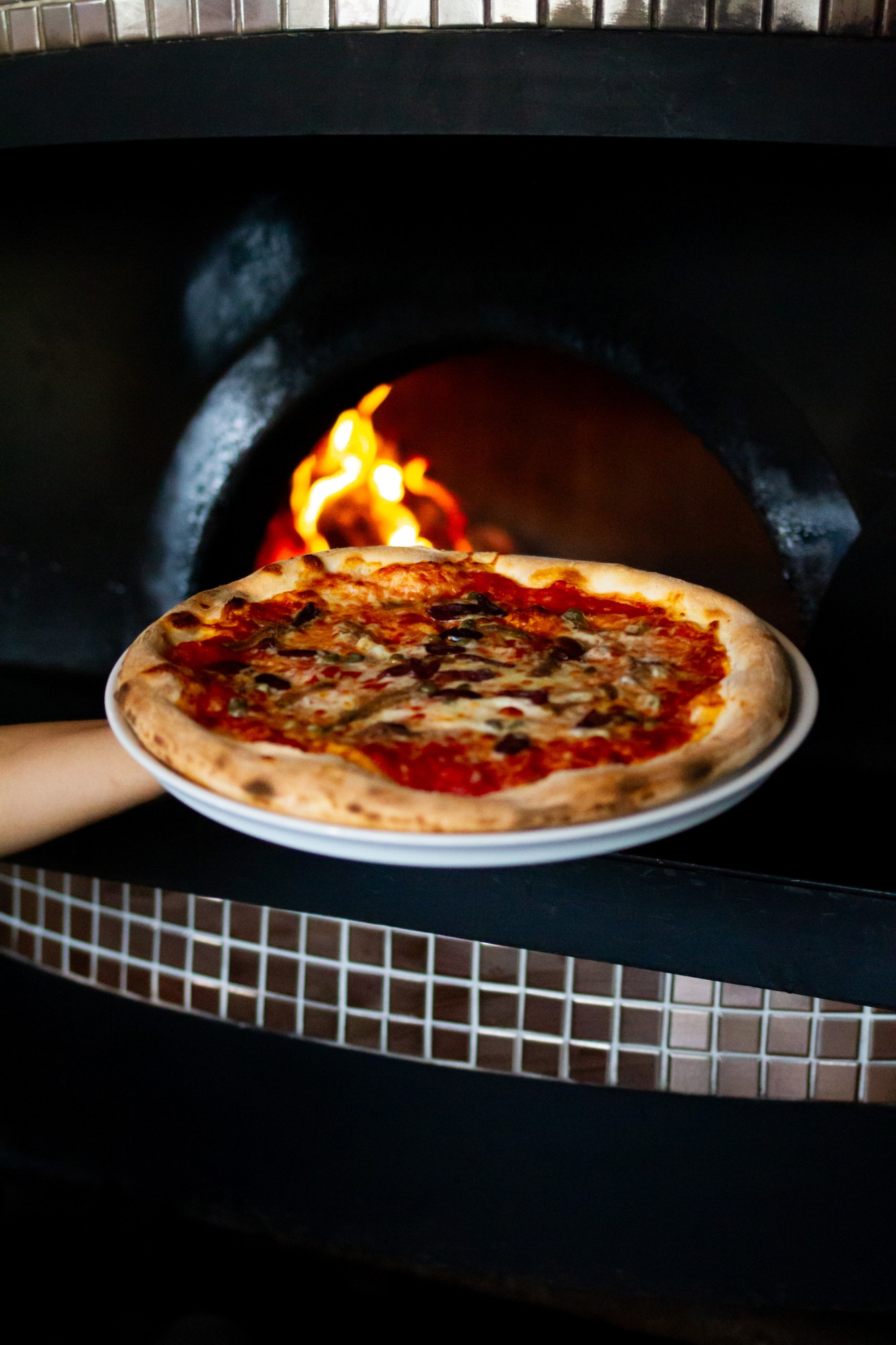 Finished pizza plated in front of the wood-fired oven